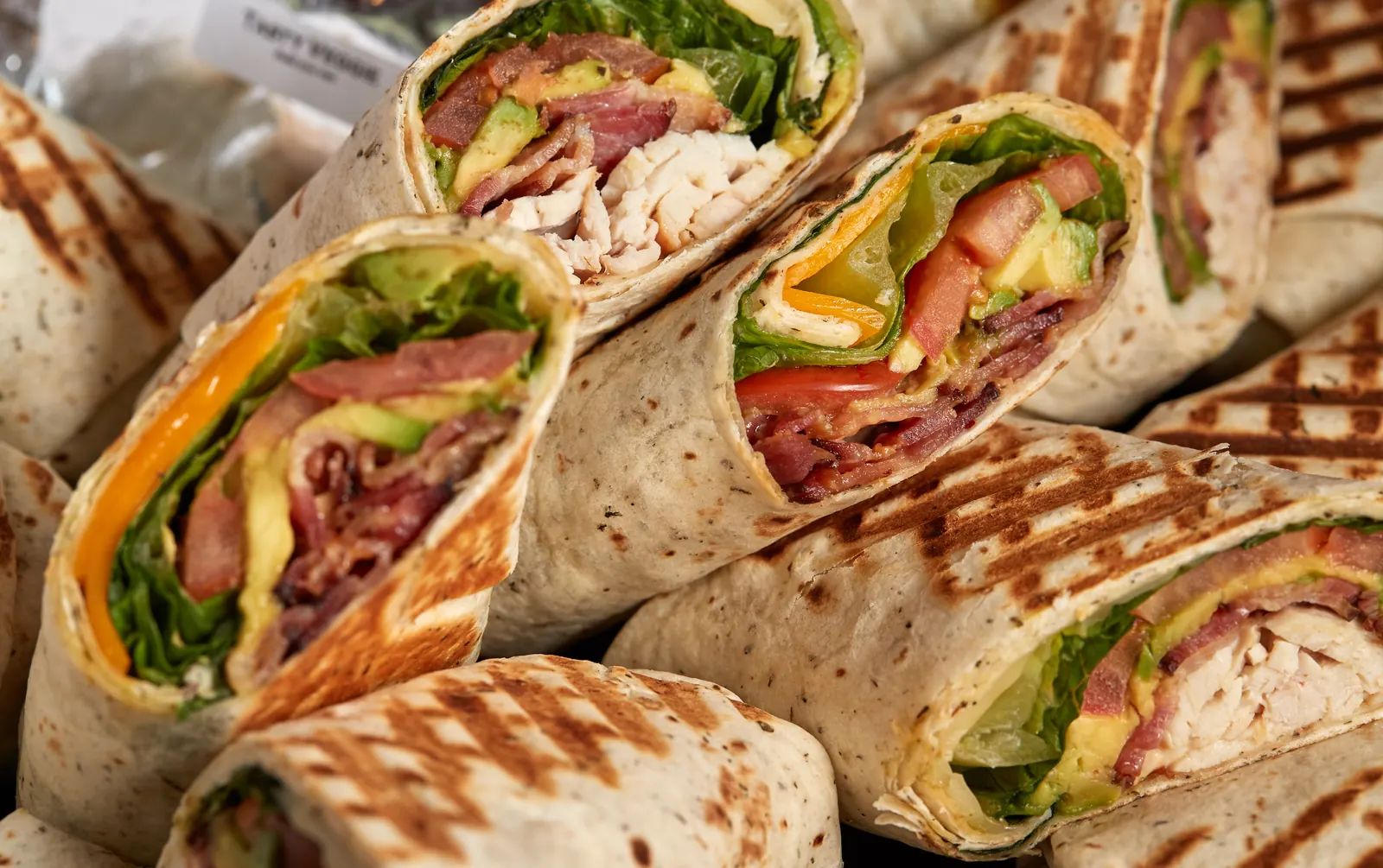 A platter of grilled wraps, cut to show turkey, bacon, avocado, tomato and cheddar.