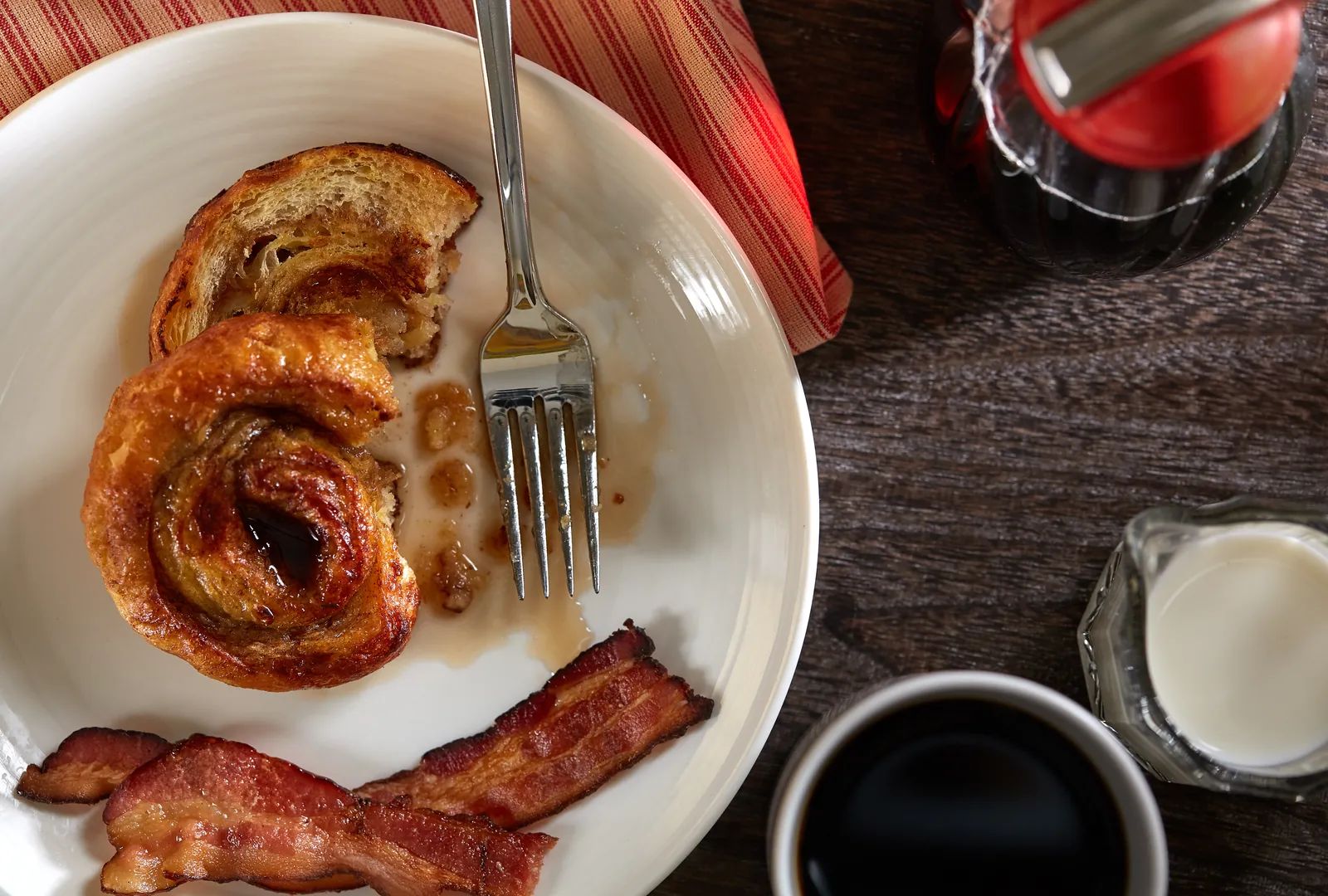 A French Toast Duffeyroll with bacon, syrup and coffee, from above.