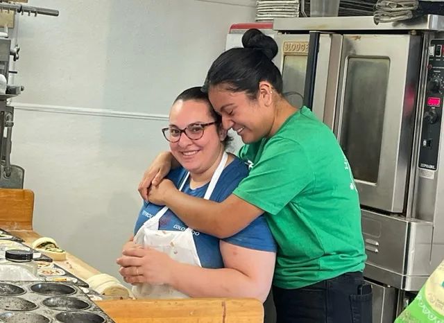 Two Hampden bakers sharing a hug by the ovens.
